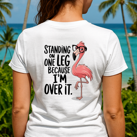 Person wearing a white t-shirt with a flamingo graphic and text in a tropical setting