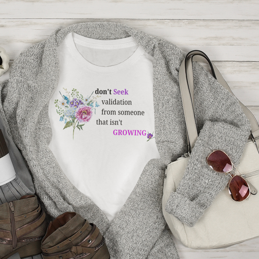 Flat lay of casual outfit with t-shirt, jeans, boots, and handbag on a wooden surface